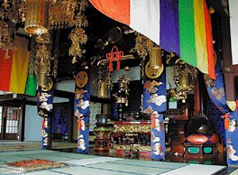 A statue of the Sacred Kannon behind the splendidly ornamented main altar or Shumidan.